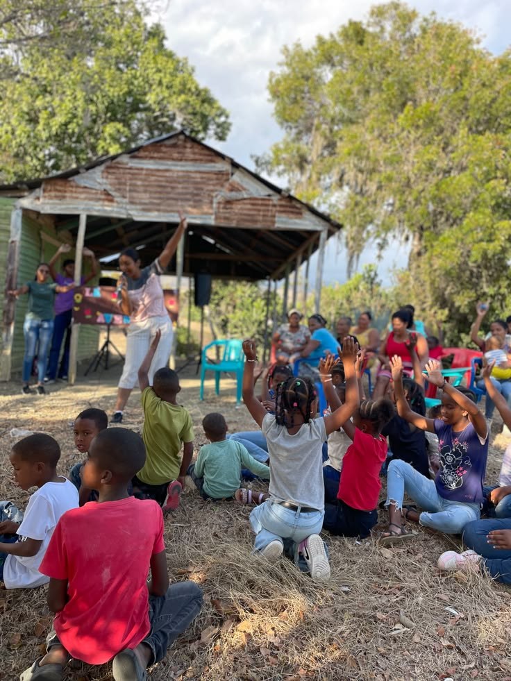 Kids raising their hands at an outdoor gathering on a mission trip