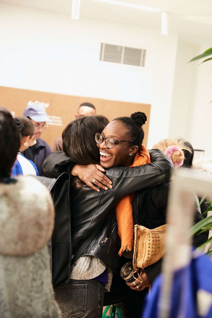 Two friends laughing mid-hug at a gathering
